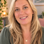 Terri Fowler smiling, with long blonde hair, a green top and a gold pendant necklace, in a room with plants